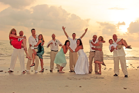 Image of a wedding party on Pass-A-Grille beach in St. Pete, with the bridal party striking various silly poses, the ocean in the background.